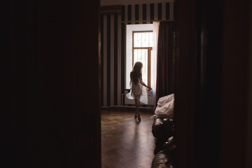 silhouette of a beautiful young girl who goes to the window