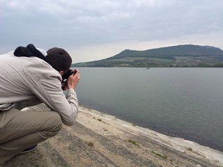 Fototapeta premium Man taking a photo of Divci hrady in Nove mlyny lake, Moravia