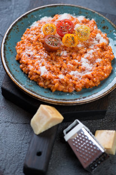 Risotto with tomatoes and parmesan served on a turquoise plate, selective focus, vertical shot