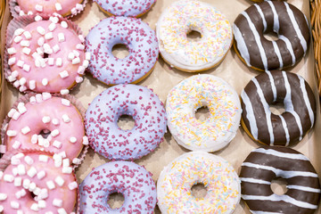 assorted donuts with chocolate frosted, pink glazed and sprinkles donuts.