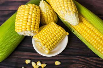 Fresh corn on cobs on wooden table, closeup, top view