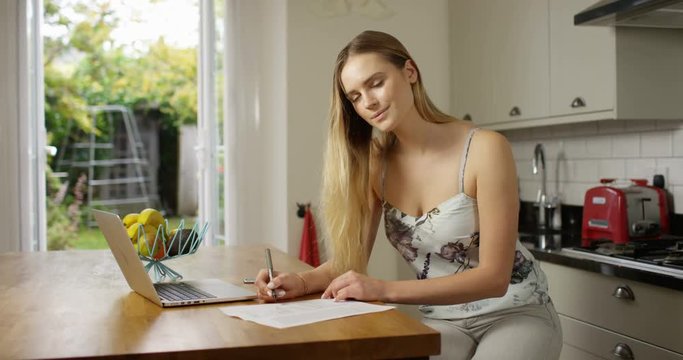 4K Portrait smiling woman working at the kitchen table, doing her household accounts. Slow motion.