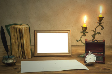The letter. Empty photo frame with copy space, book and burning candle in vintage candlestick feather pen with inkpot and pocket watch on retro wooden table background.  Education. Back to school. 