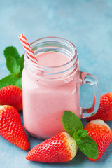 Strawberry smoothie or milkshake in mason jar on blue table. Healthy food for breakfast and snack.