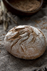 Freshly baked traditional bread and Wheat Ears on the Wooden Table. Harvest and Bakery concept. Close-up on a vintage wooden background, selective focus, shallow depth of field.