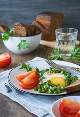 Fried egg with green peas and fresh tomatoes on a plate                     