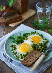Fried eggs with green peas on a plate      