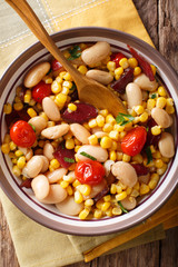 Traditional succotash of corn, butter beans, tomatoes and bacon close up in a bowl. Vertical top view