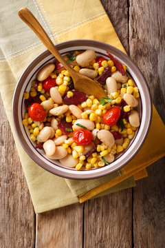 succotash of corn, butter beans, tomatoes and bacon close up in a bowl. Vertical top view
