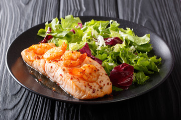 Healthy food: Baked salmon fillet with shrimp and fresh lettuce on a plate close-up on the table....