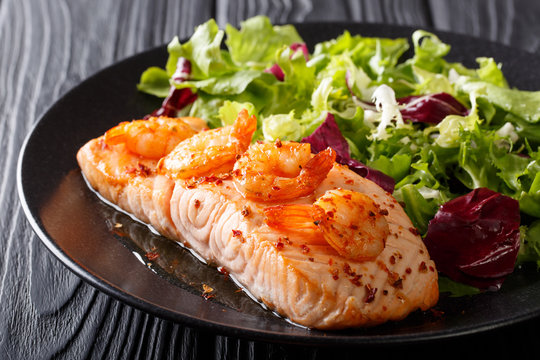 baked fillet of salmon with prawns and cayenne pepper and fresh salad on a plate close-up. horizontal