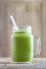 Fresh organic smoothies from avocado, banana, dill, broccoli and honey in glass mug on wooden table. Close up