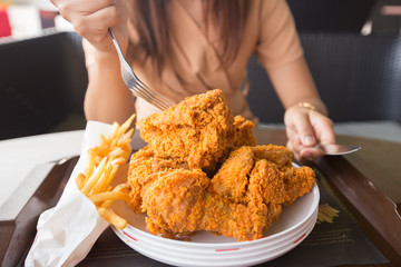 Fried chicken in young woman hand select focus, Hand with fried chicken blur background, Close-up Fried chicken