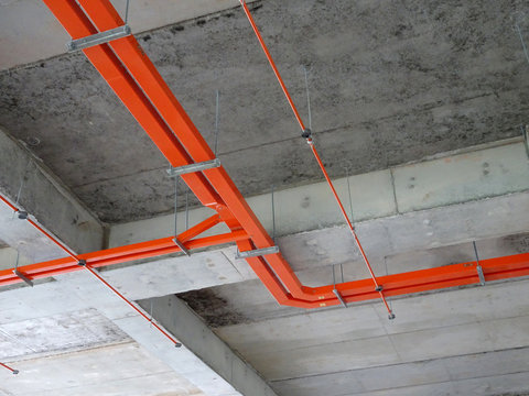 Construction workers installing electrical conduit and cable tray made from metal.  