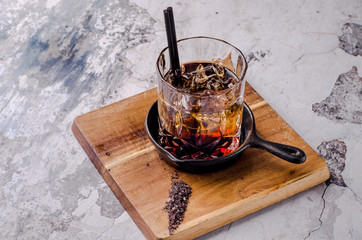 Close up, brown alcoholic cocktail with whiskey, ice cubes decorations on a wooden board, gray...