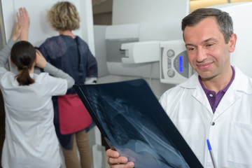 Obraz premium Radiographer looking at xray, patient in background