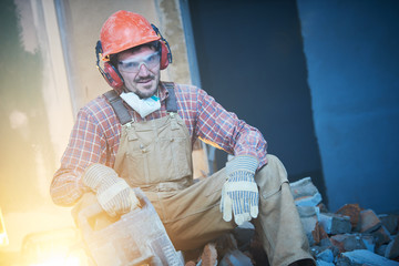 breaking interior wall. worker portrait with demolition hammer