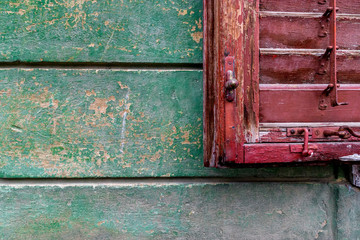 Old red window blind on a green wall