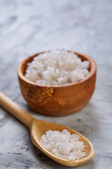Fototapeta na wymiar Large white sea salt in a natural wooden bowl on white background, top view, close-up, selective focus