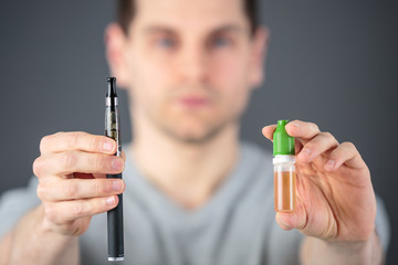 man showing an adjustable electronic cigarette and its liquid