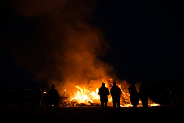 silhouettes of people in frontof big fire