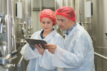 scientist speaking to his colleague holding clipboard in the factory