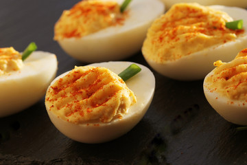 deviled eggs with red pepper on black background