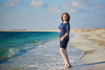 Fototapeta na wymiar Happy pregnant woman on the beach near the sea