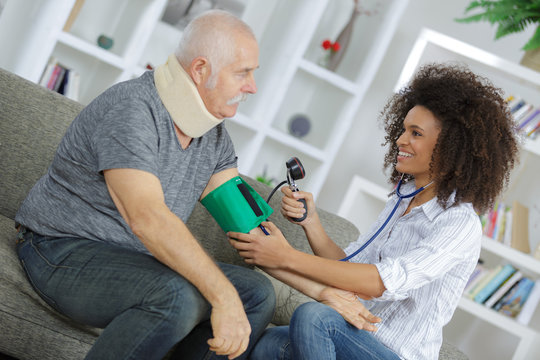 Young lady taking man's blood pressure at home