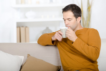 Man on sofa drinking from cup