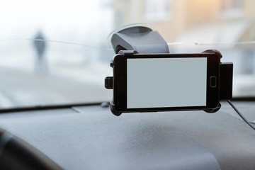 Car smartphone holder with phone attached to the windscreen of automobile. Accessories for vehicles, for ease of control a car in the way. Phone holder with charging function