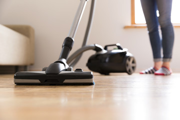 People, housework and housekeeping concept - happy woman with vacuum cleaner at home. Spring...