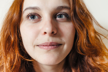 Portrait of beautiful cheerful redhead girl with curly hair over beige background. Hair dyed with henna. Professional hair care.