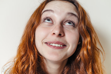 Fototapeta premium Portrait of beautiful cheerful redhead girl with curly hair over beige background. Hair dyed with henna. Professional hair care.