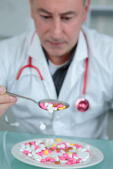 doctor holding a tea spoon of colorful pills