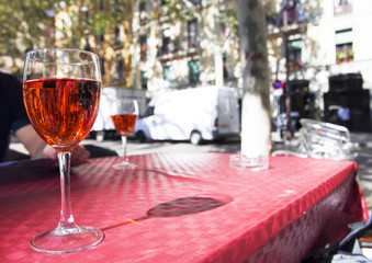 a glass of red wine on the table of a street cafe on a bright sunny day
