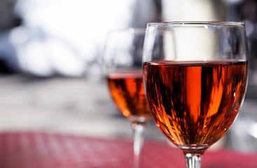 two  glasses of red wine on the table of a street cafe on a bright sunny day