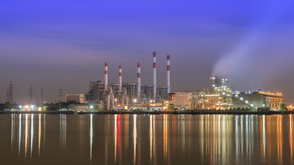 Factory in night time beside big river.