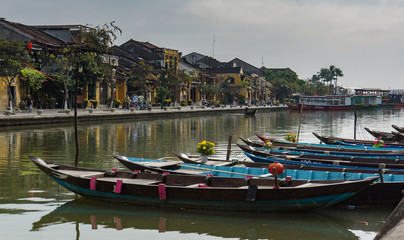boats with yellow flowers and lanterns tied up along the river in old town of Hoi An, Vietnam
