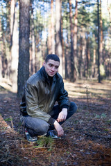 Naklejka na ściany i meble A young man of criminal appearance in a black leather jacket posing in an autumn forest.