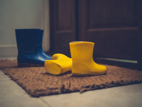 Two pairs of rubber boots by door