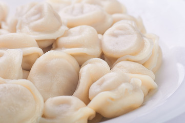 Fototapeta na wymiar Appetizing dumplings, vareniki, ravioli, momo close-up. Traditional dish of Russia, Italy, Asia. Boiled dough with filling. Dumplings with meat, fish, vegetables. A hearty breakfast, lunch, dinner.