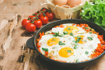 Tasty and Healthy Shakshuka in a Frying Pan. Fried eggs with tomatoes, bell pepper, vegetables and herbs. Middle eastern traditional dish.
