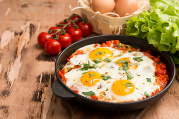 Tasty and Healthy Shakshuka in a Frying Pan. Fried eggs with tomatoes, bell pepper, vegetables and herbs. Middle eastern traditional dish.