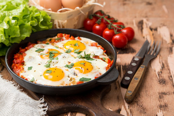 Tasty and Healthy Shakshuka in a Frying Pan. Fried eggs with tomatoes, bell pepper, vegetables and herbs. Middle eastern traditional dish.