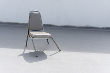 broken dead leather white chair on an outdoor concrete floor., with copy space for text.