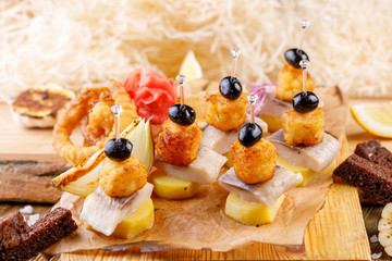 Original appetizer of canap with salted herring and cards of the potato. Rustic.