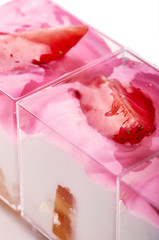 Light air dietary dessert. Delicate sweet white and pink cream with fruits and berries. Delicious treat is decorated with a piece of fresh strawberries. Portion dessert in a transparent glass.