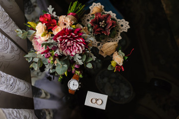  wedding bouquet with flowers on the glass table near watch and rings