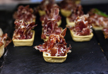 Tha sliced ham (jamon) on the black plate with melon on the market